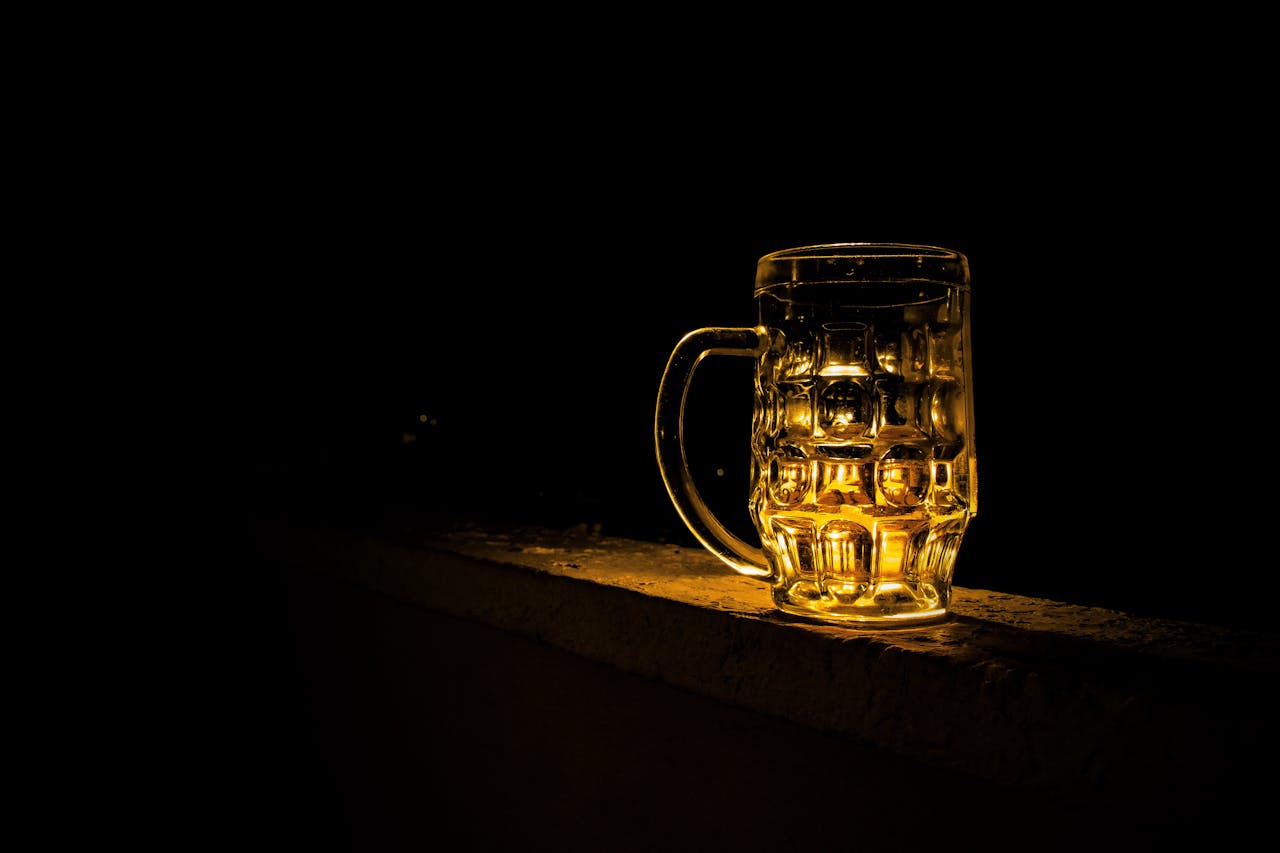 gallery-5 A glass beer mug illuminated against a dark background, creating a moody atmosphere.