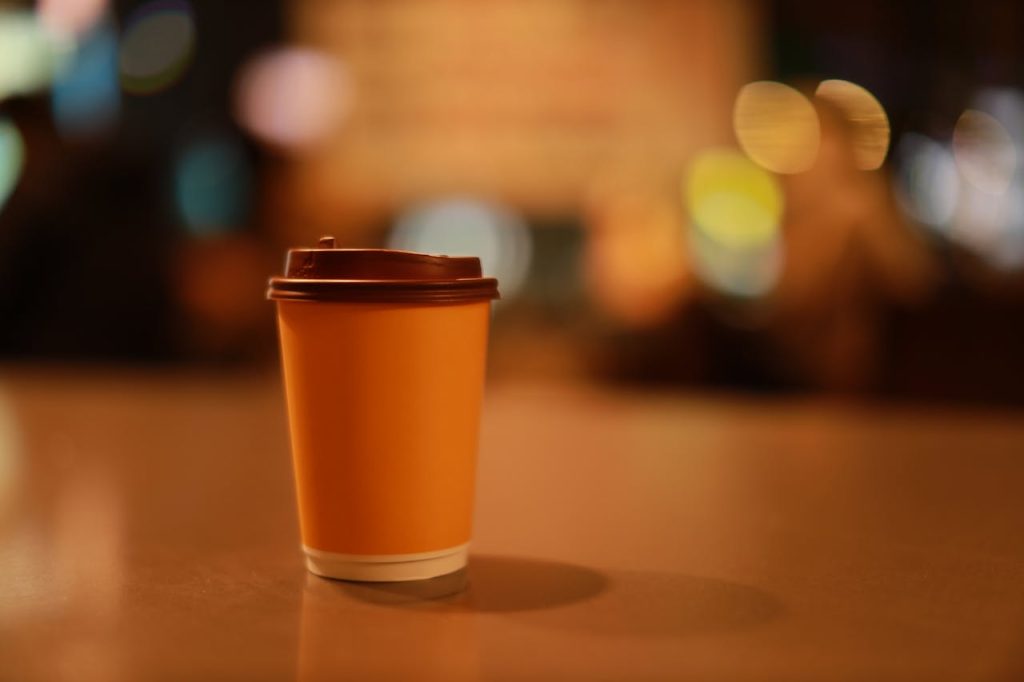 Disposable coffee cup with blurred bokeh lights in Taipei at night.