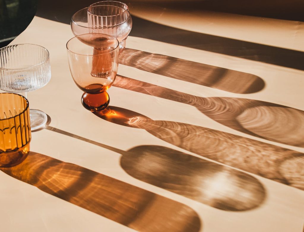 Elegant glassware casting artistic shadows in warm sunlight on a minimalist table.