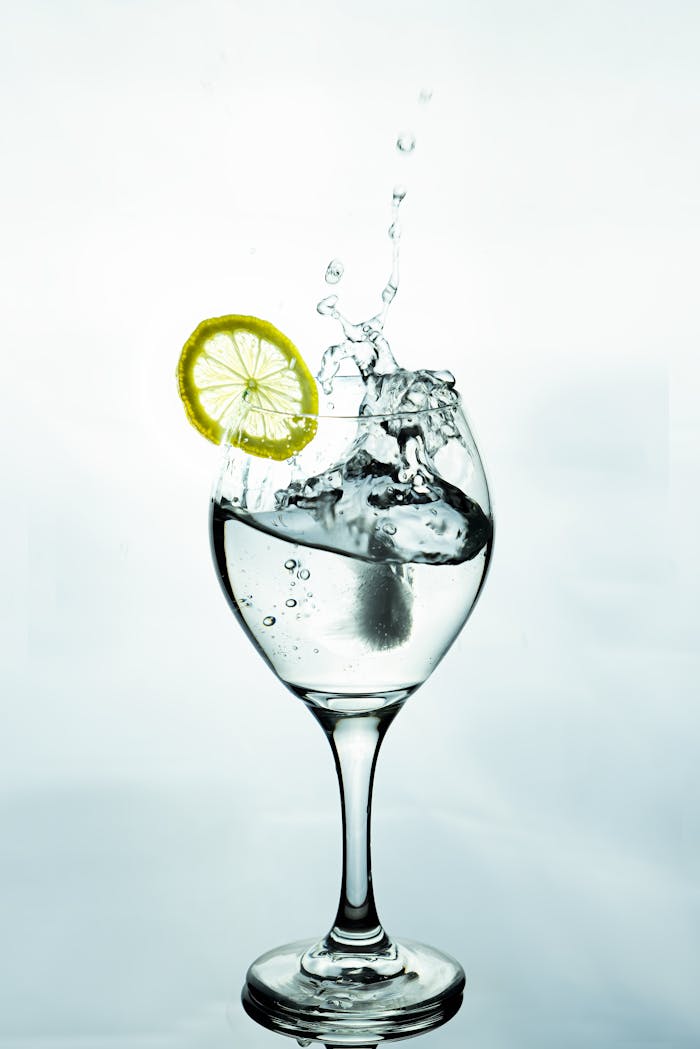 gallery-1 A lemon slice splashes into a glass of water, creating dynamic ripples and bubbles.