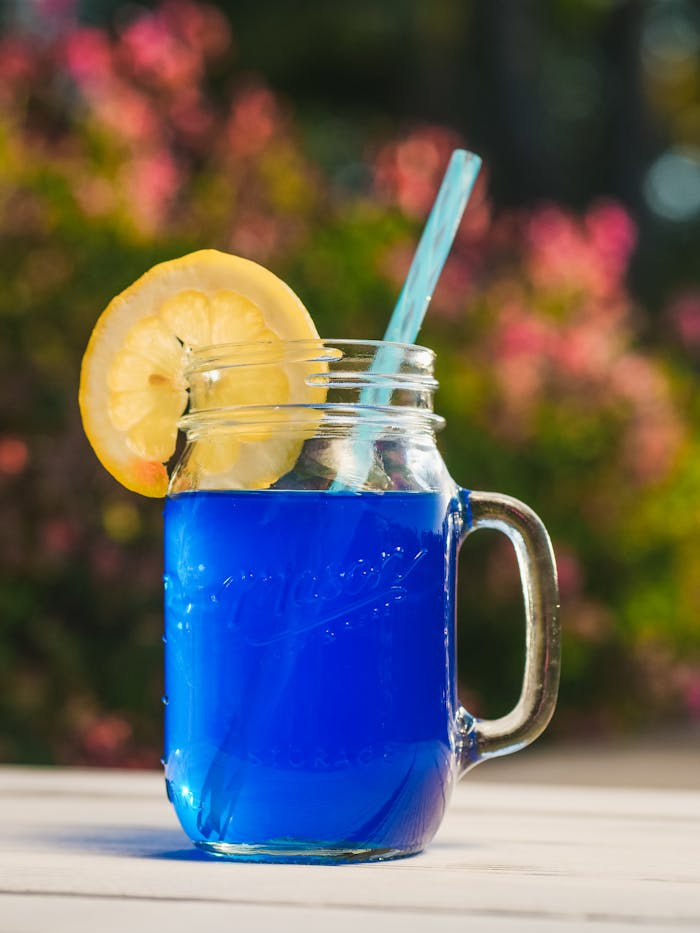 Bright blue lemonade with lemon slice in a mason jar, perfect for a refreshing summer day.
